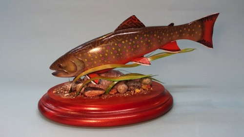 12 inch Brook Trout swimming through  grass. The grass is made from paper and the rocks are carved from Basswood.